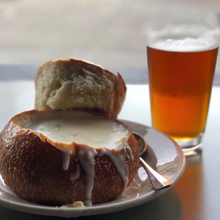 San Francisco clam chowder in a bread bowl with a glas of beer in the background